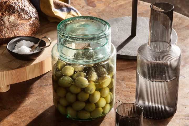 One of the autumn interior design trends 2021 is to find connection in the kitchen by investing in fine porcelain or like here - Ferm Living's Ripple glass and carafe or storage jar from Ferm Living to store olives in.