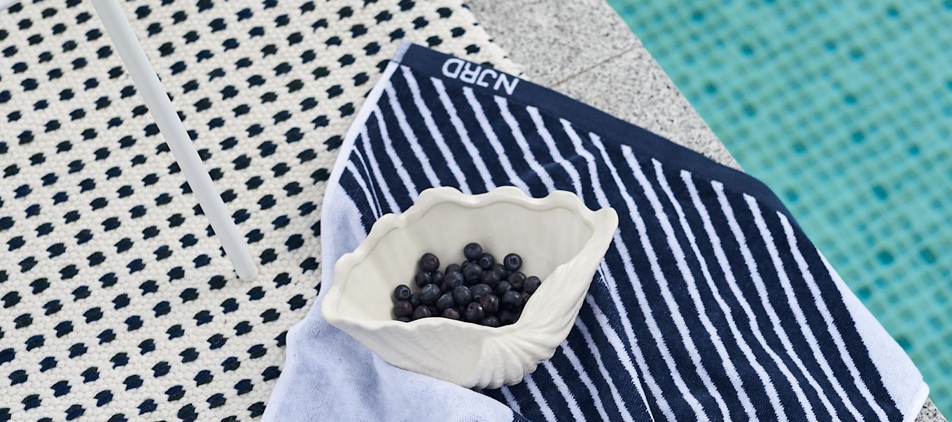 The blue Stripes towel from NJRD together with the Shell bowl from By On are the perfect Mediterranean decor.