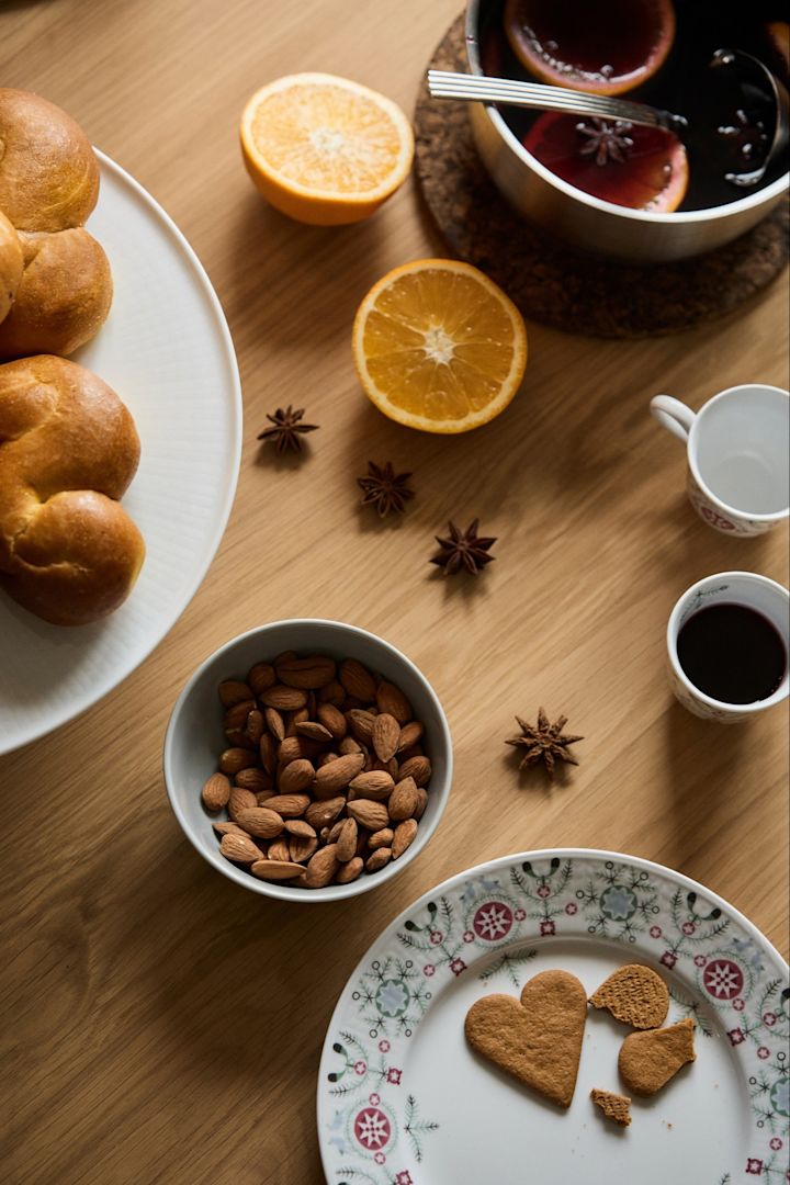 A winter party preparation scene with saffron buns, mulled wine and almonds photographed from above. 