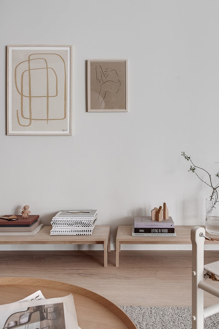 A living room decorated in the Japandi style with low furniture in pale wood with clean line art work. 