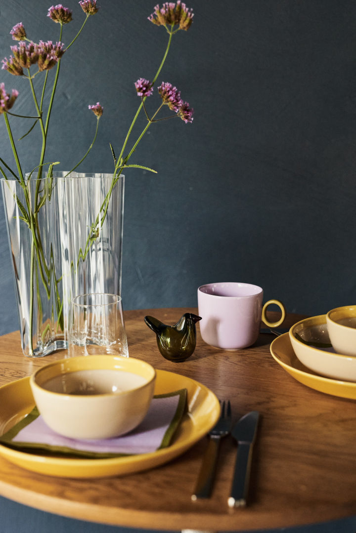 Here you see a yellow table setting idea with contrasting purple mugs and a moss green glass bird in a retro diner style setting. 