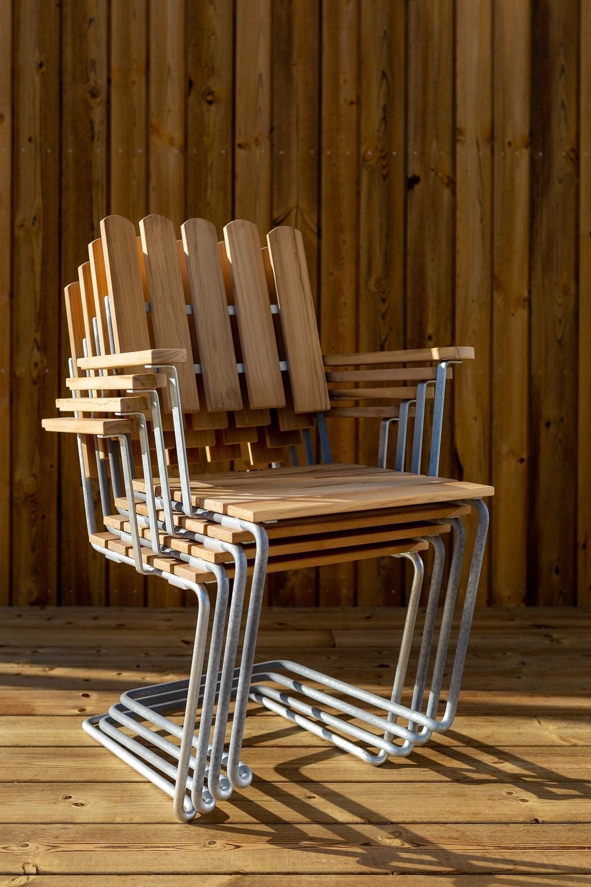 Grythyttan Reportage: Here you can see stacked A2 chairs with wooden armrests standing on a terrace.