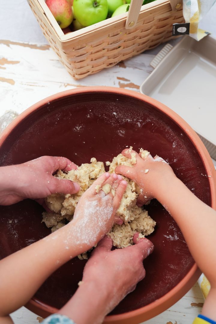 Picture showing hands kneading and mixing crumble dough for an apple pie, here in the Knabstrup dough bowl.