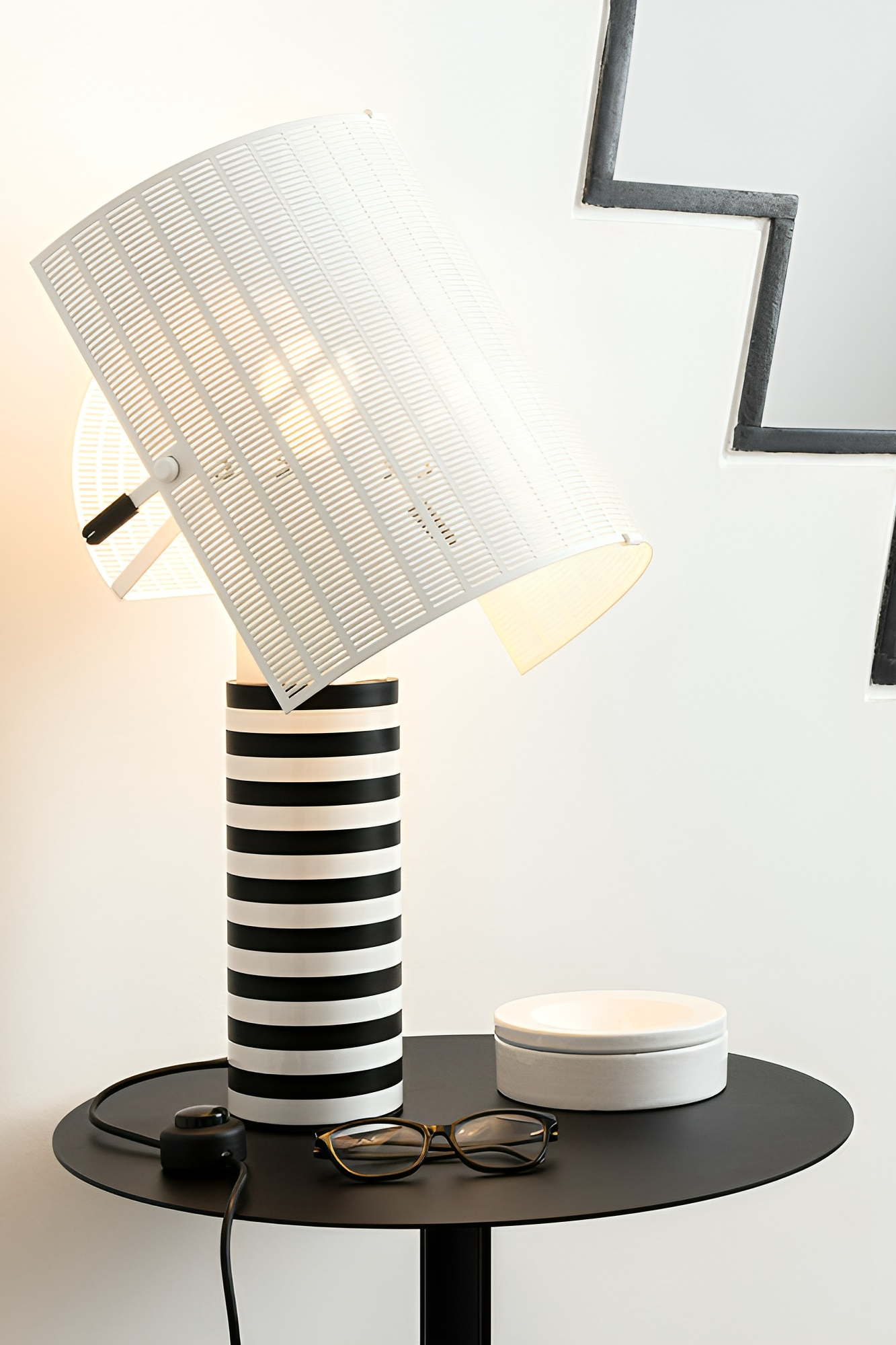 The Shogun table lamp from Artemide with black and white stripes stands on a side table. 