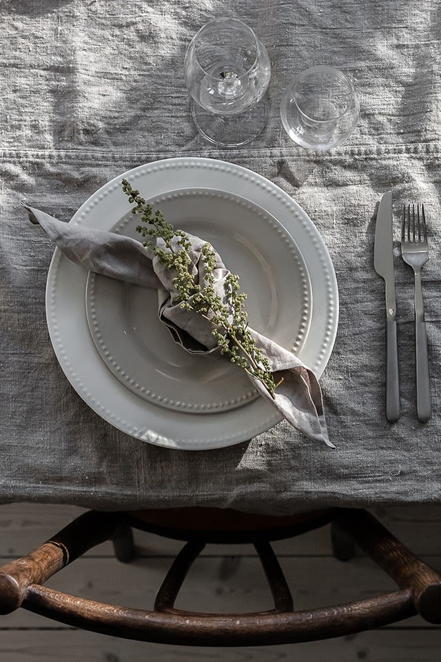 Here you see a grey napkin folded into a rustic knot with a flower from the garden. 