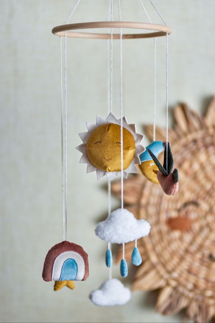 A close up of a mobile from Bloomingville with rainbows, rain clouds, a sun and a bird. Mobiles are very nice baby shower gift ideas. 