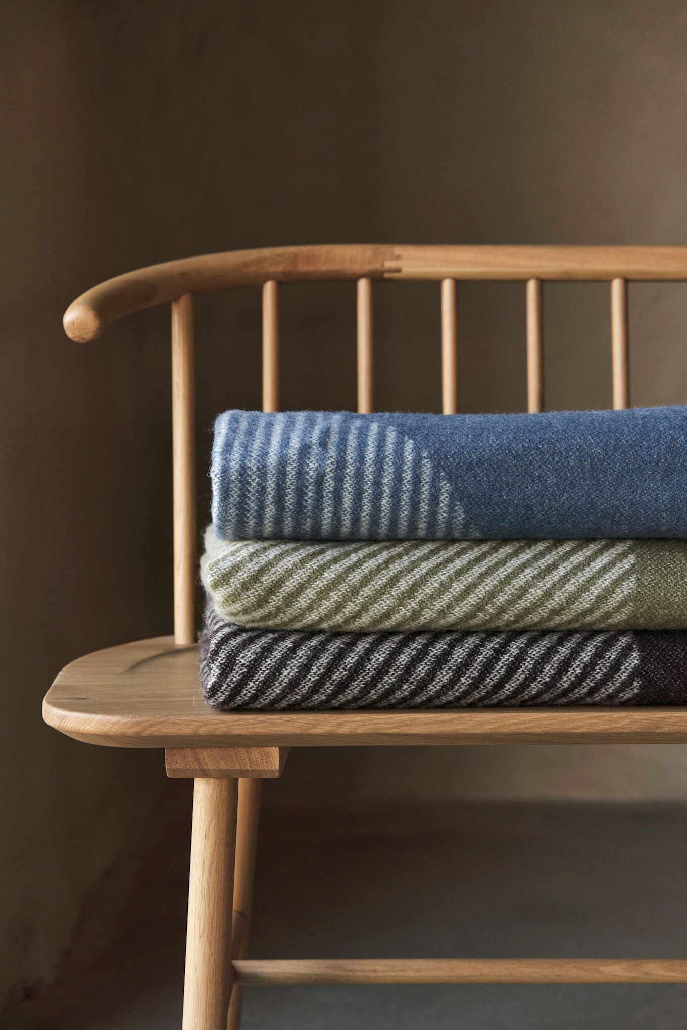 The NJRD Stripes cotton throw in pale yellow and pastel blue draped over a chair at a dining table.