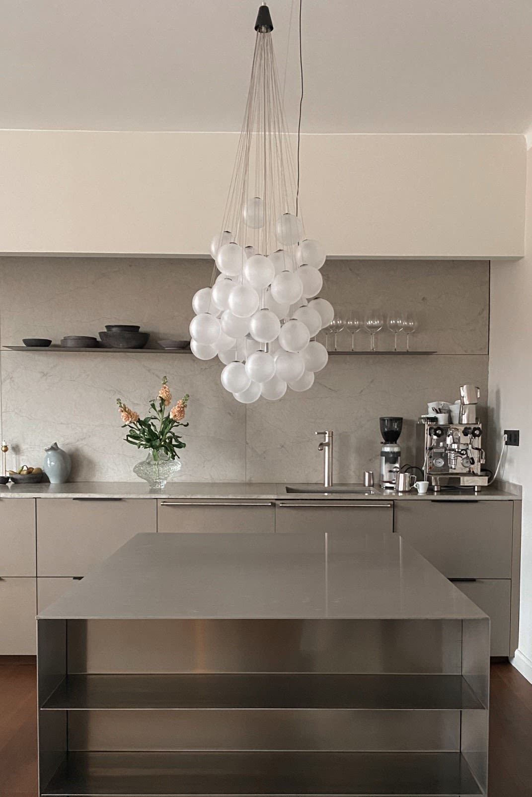 Refresh your home with modern lighting design. Here you see the Stochastic ceiling lamp from Luce Plan, a collection of glass balls hanging in a group above a stainless steel work bench. 