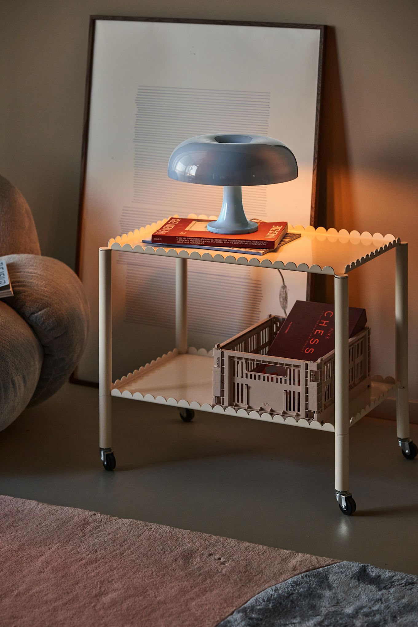 The Nessino lamp illuminated on a desk with an open magazine and a stack of books. 