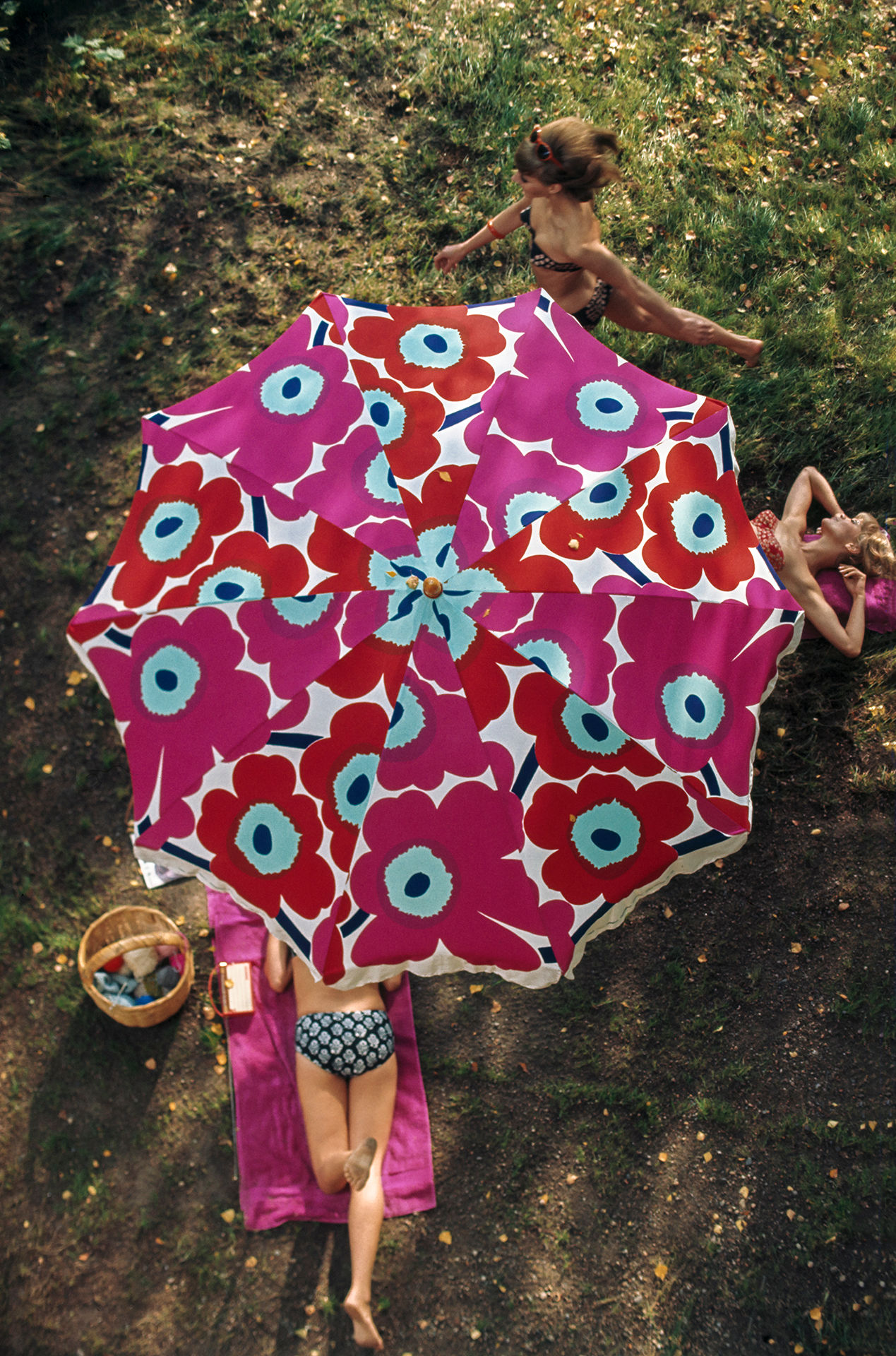 An image of a Unikko parasol from above with woman laying in the sunshine underneath. 