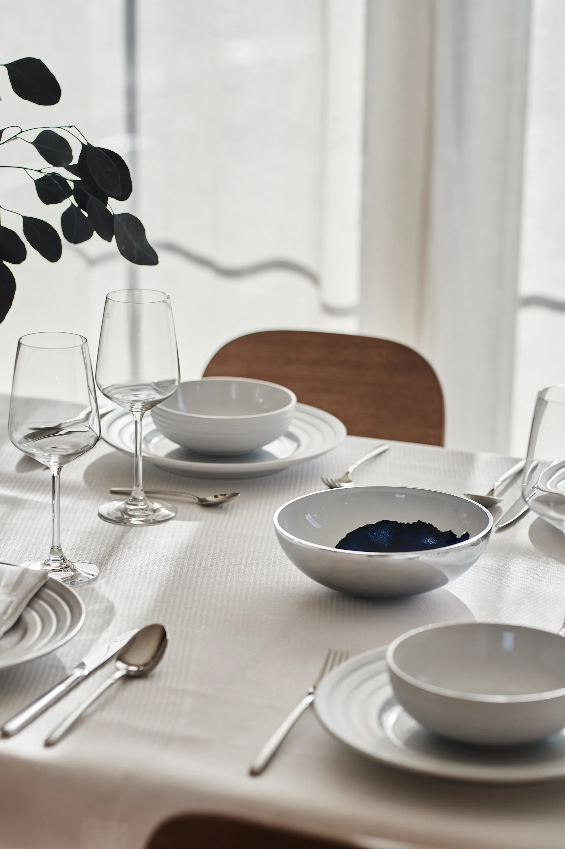 A white table setting with porcelain from NJRD and linen napkins and tablecloth from Scandi Living.