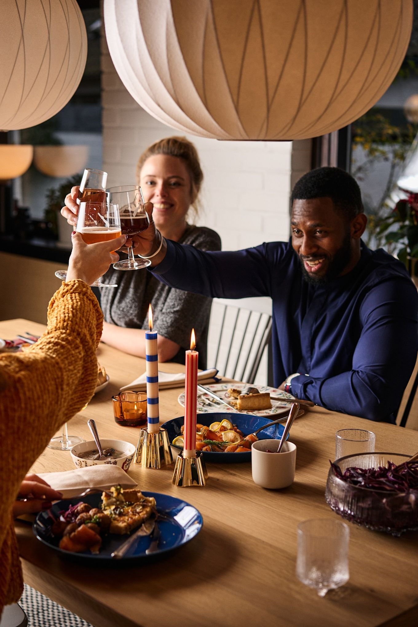 Friends cheers over a Nordic Christmas table with colourful plates and Christmas food. 