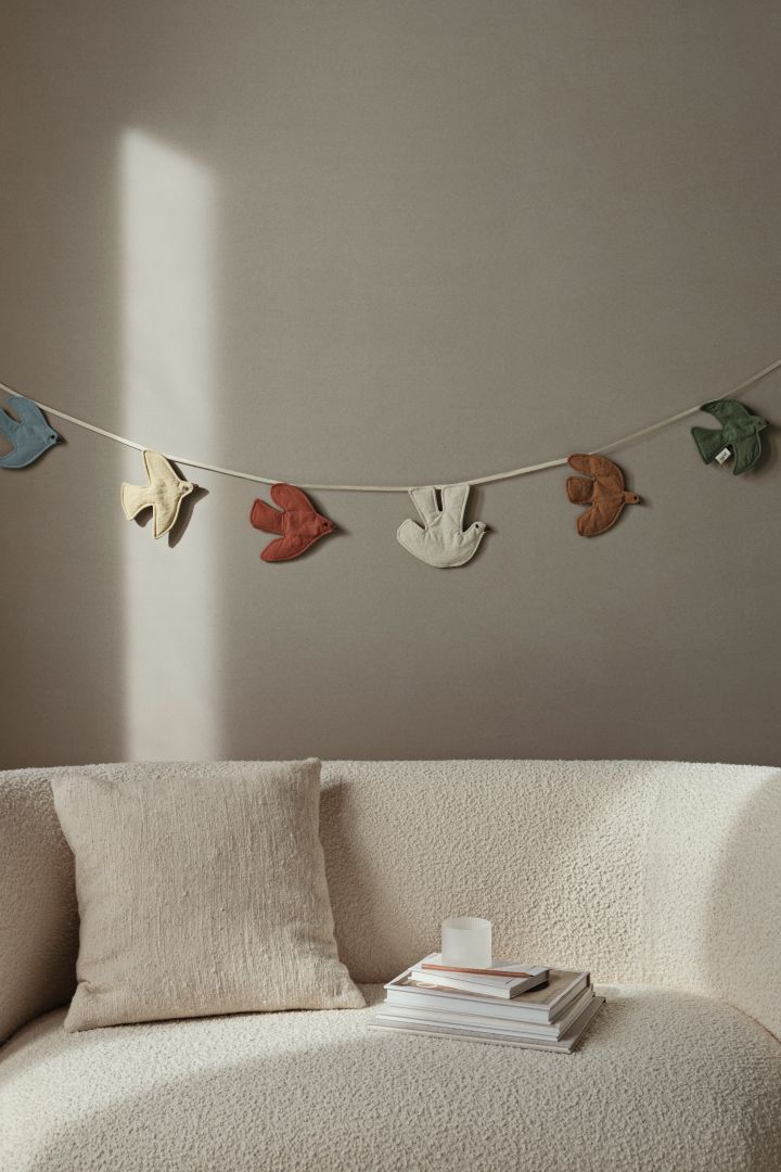 The swift bird garland hangs on a neutral beige wall bringing both colour and interest to a children's room. 