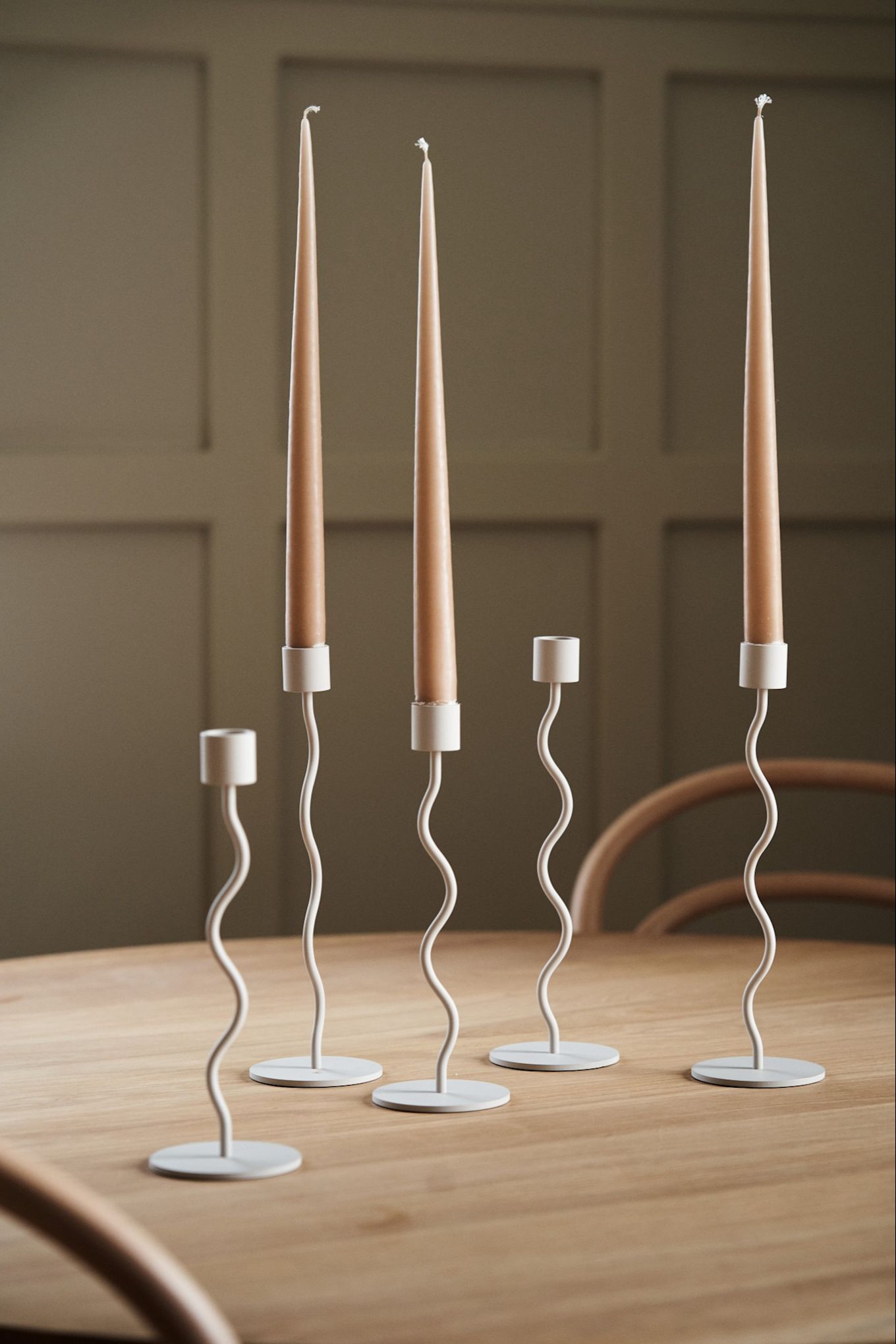 A collection of the Curve candle holders in beige from Cooee Design on a wooden dining table. 