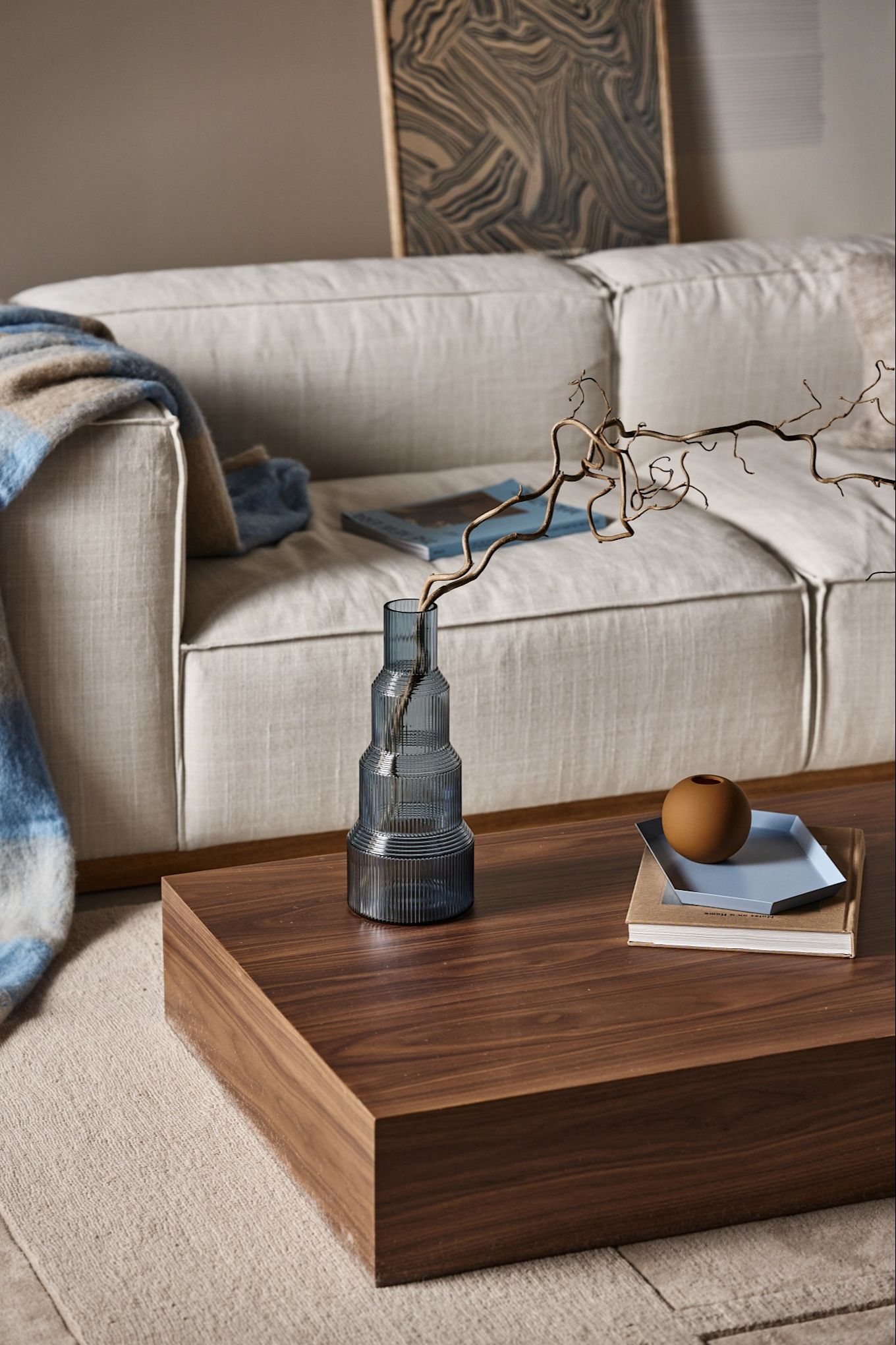 Subtle shades of powder blue are one of the interior design trends for autumn 2024, here you see the Pavillion vase from Orrefors stood on a wooden coffee table in a neutral beige coloured living room. 