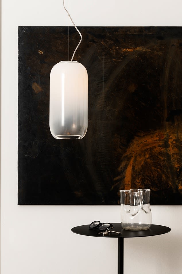 The Gople pendant lamp hangs over a side table with a clear glass vase. 