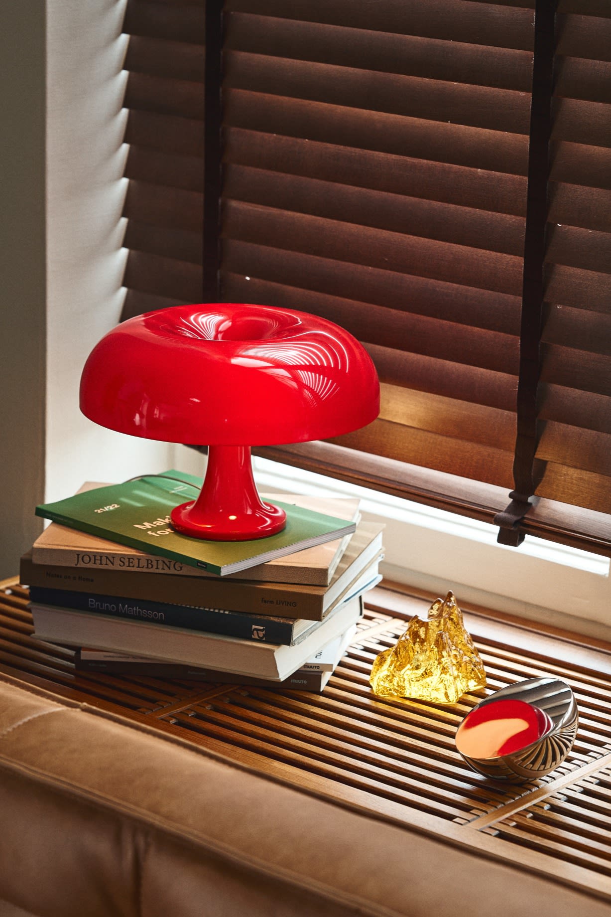 Update your home with modern lighting ideas like the Instagram favourite Nessino in red from Artemide. Seen here on a wooden windowsill with a yellow candle holder from Kosta Boda. 