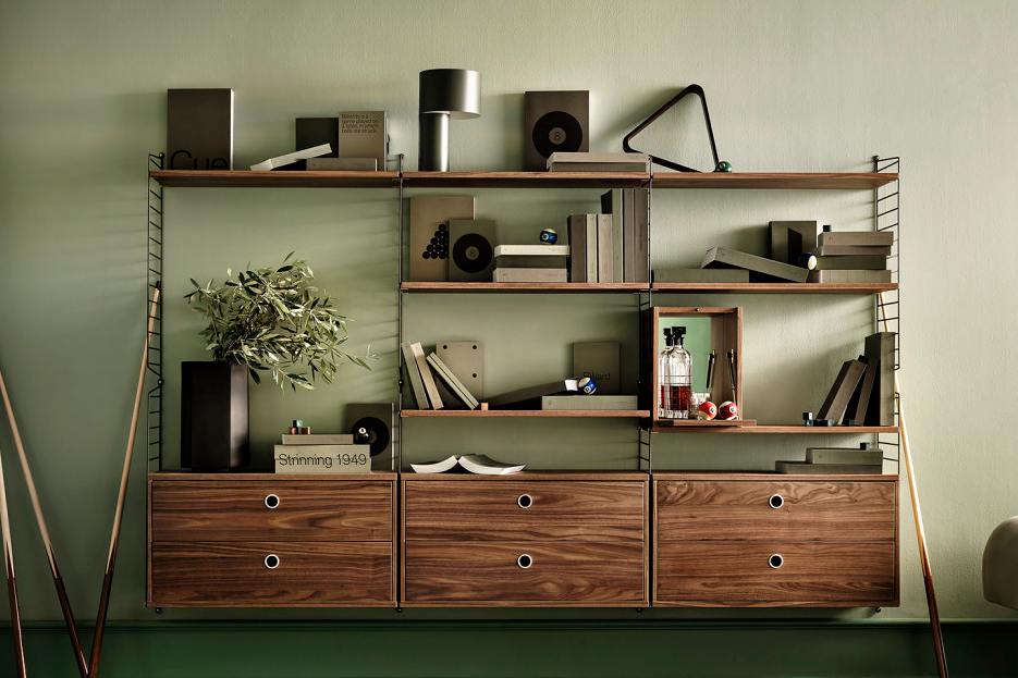 String shelf system in walnut build as a bookshelf with both open and closed storage possibilities.