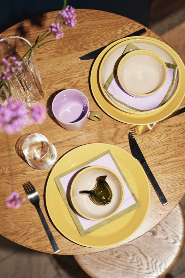 A yellow table setting idea, seen here from above. The yellow plates from the Play collection combined with a purple mug and napkin and a quirky glass bird. 