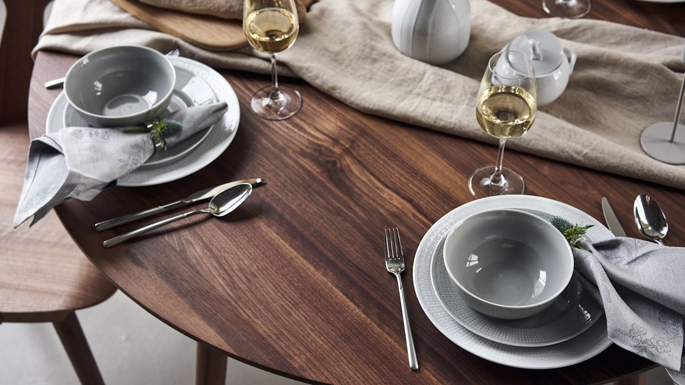 A festively set table with Swedish Grace porcelain in white and grey with linen napkins by Rörstrand and white wine glasses by Scandi Living. 