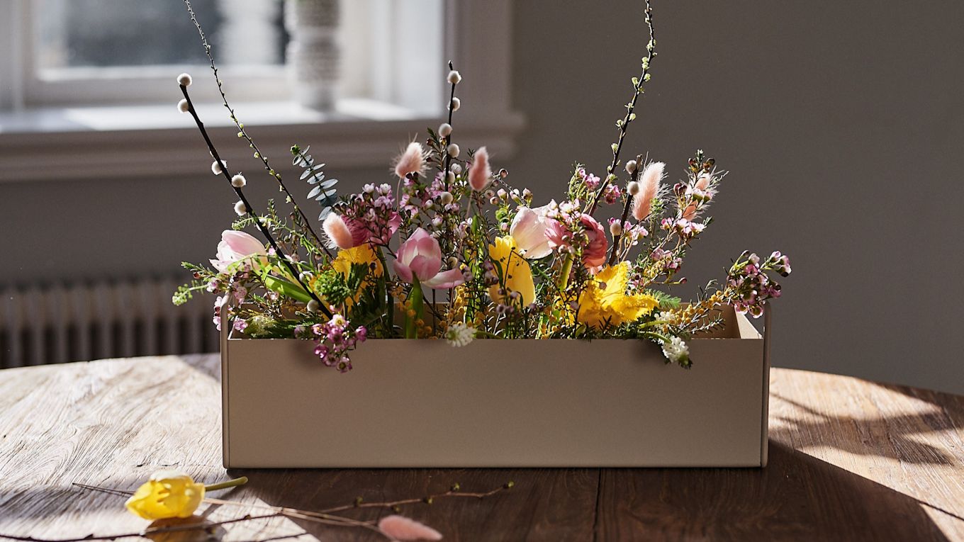 Small beige Plant Box from Ferm Living stands on the table with spring flowers in it for interior design inspiration for spring. 