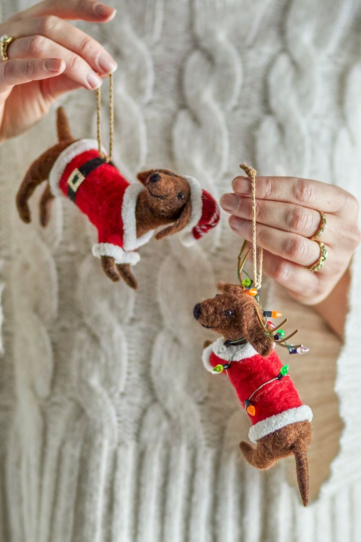 Here you see hands holding two felt sausage dog, quirky, playful Christmas tree decoration ideas.