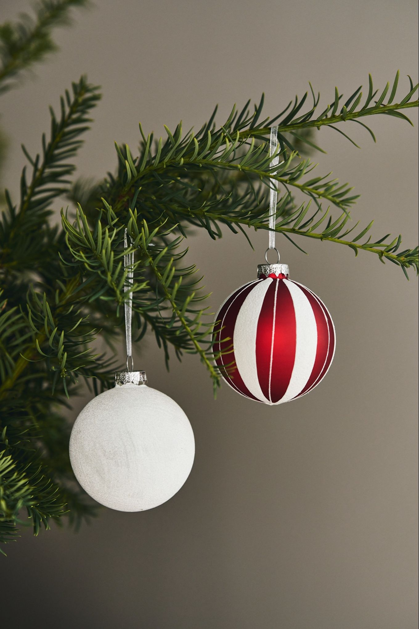 Here you see playful and colourful Christmas tree decoration ideas - a red and white striped bauble from Scandi Living and a white glittery bauble also from Scandi Living. 