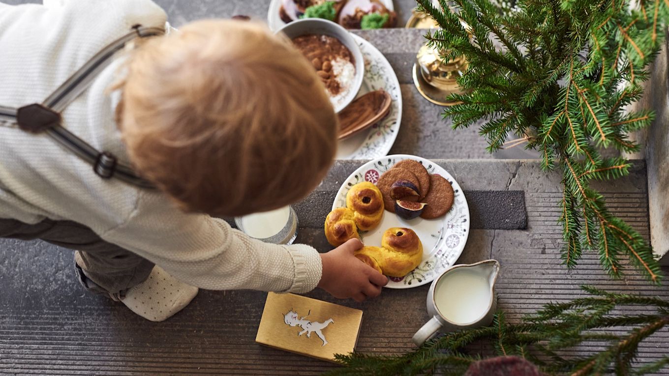 Here you can see a child reaching for a lussekatt on a plate from Rörstrand's Swedish Grace Winter collection.