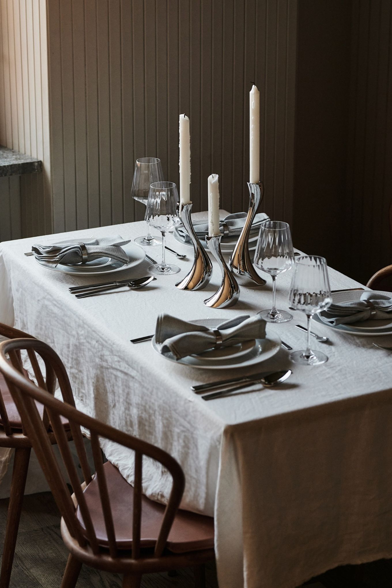 A white table setting idea with a crisp white tablecloth and complimentary chrome details for a restaurant style table setting at home. 