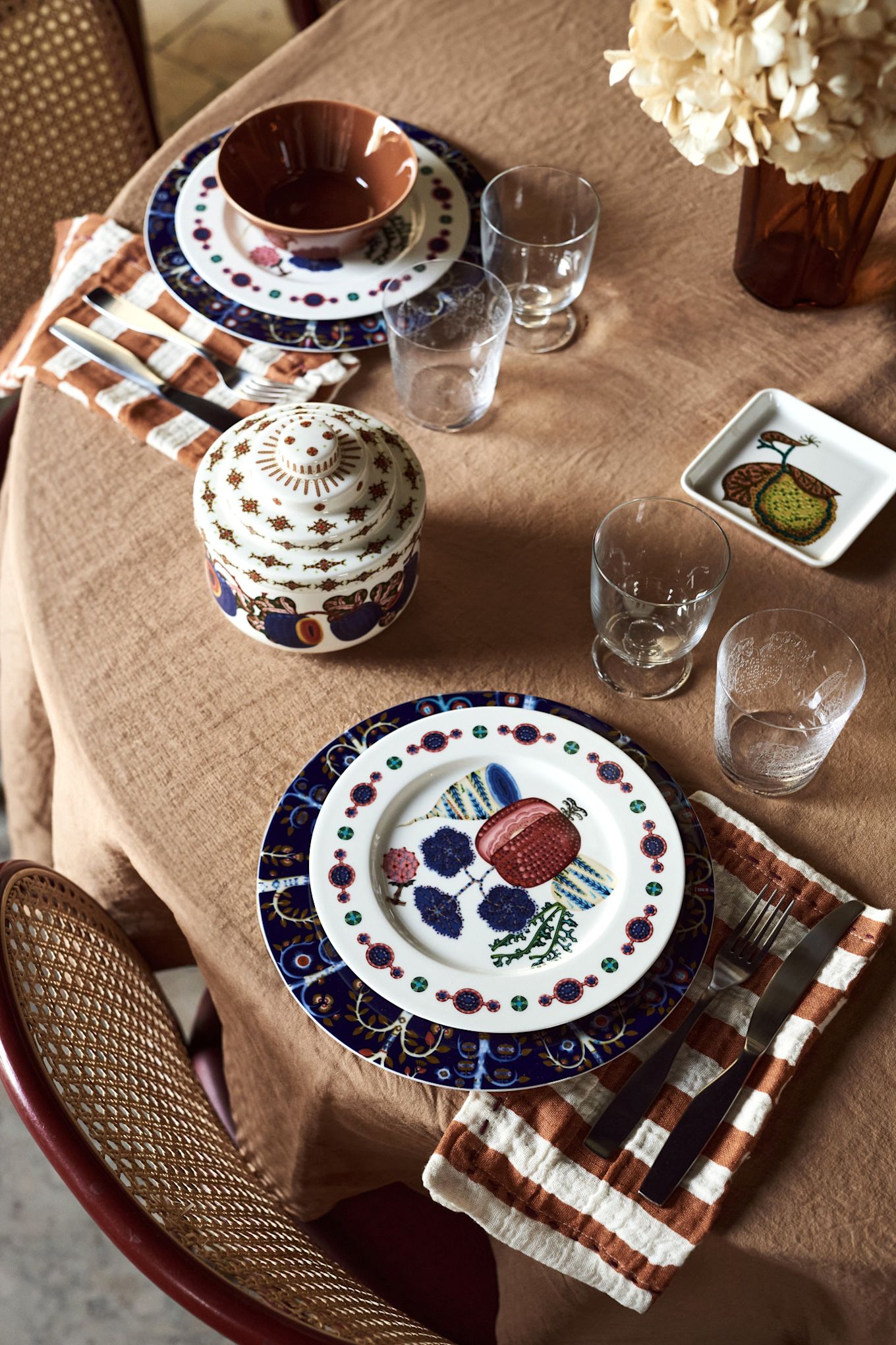 A bohemian table setting idea seen from above with patterned plates and a brown tablecloth. 