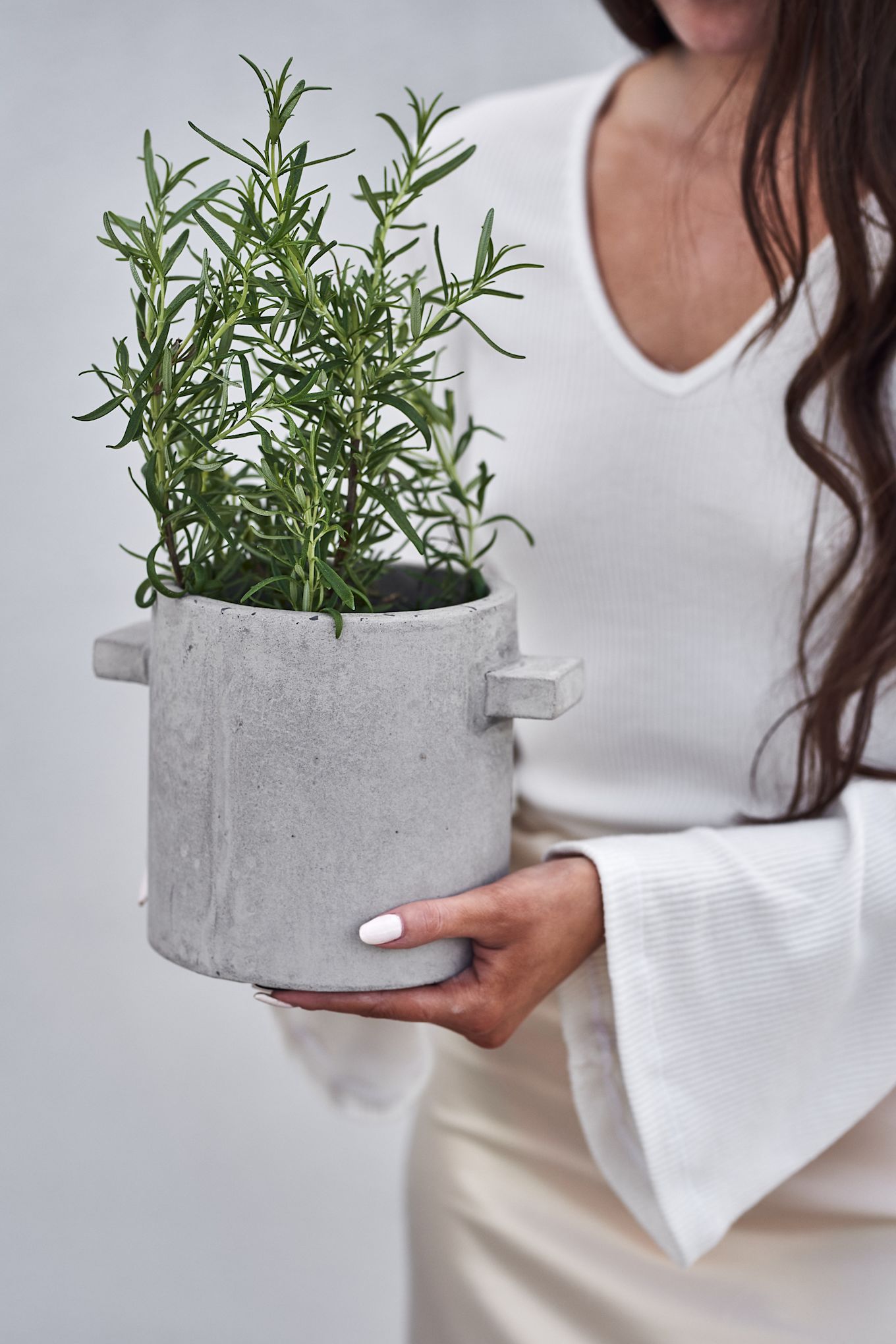 Plant pots for your herbs on the balcony are an absolute summer essential. Here you see the Serax concrete pot with a aromatic rosemary plant. 