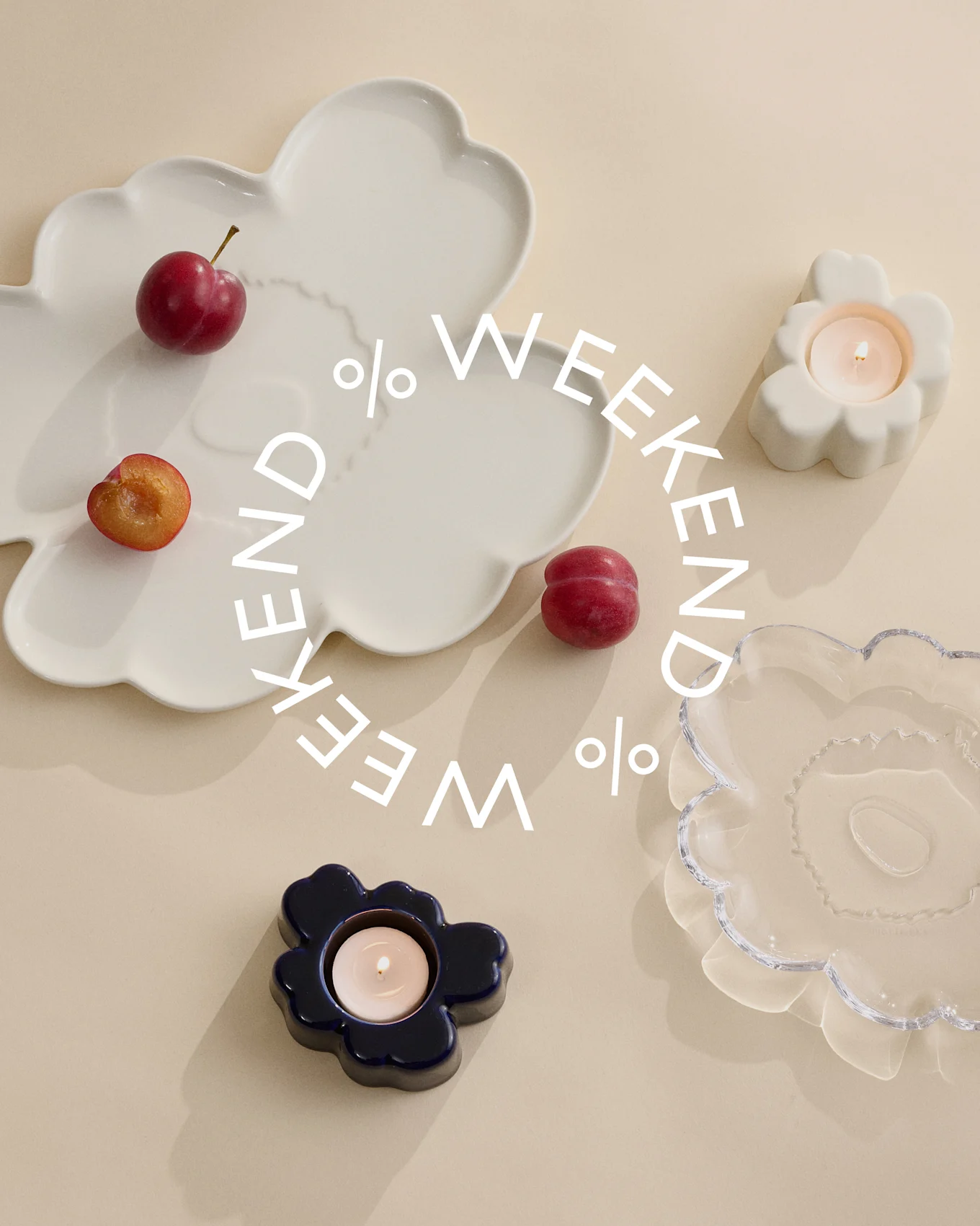 Decorative plates and candle holders in white, blue, and clear glass with plums on a beige background. White text says 'Weekend %'.
