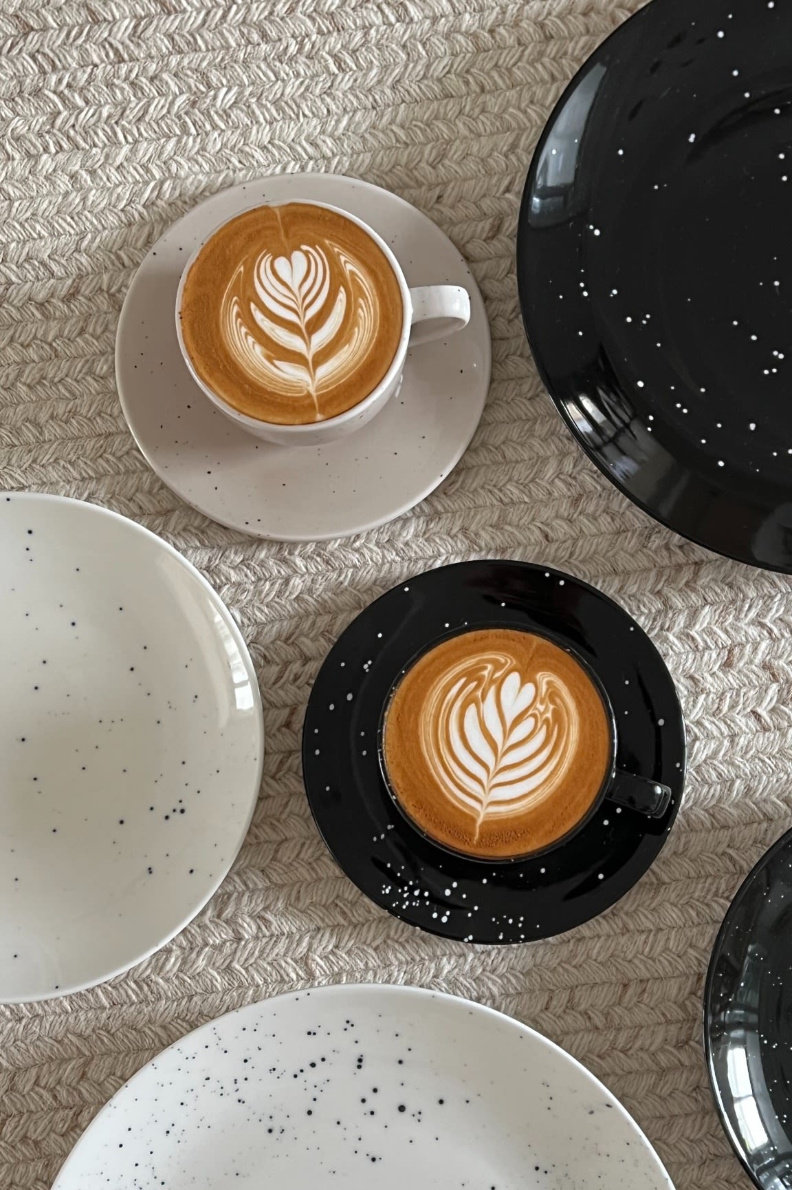 Two cups of artfully arranged coffee in black and beige from Scandi Living's Freckle collection surrounded by plates in @Avery-P's home.