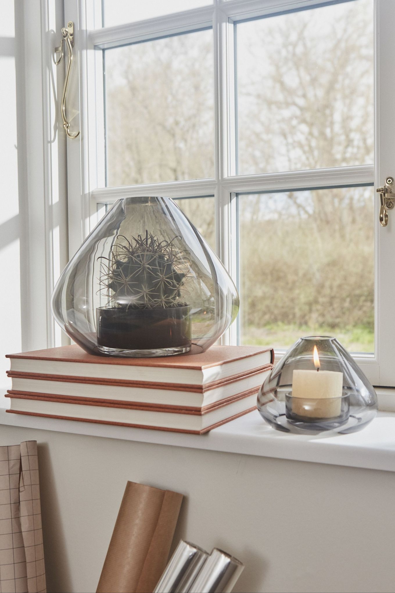 Here you can see the Uno lantern from AYTM in two different sizes standing on a windowsill.  The large one has been placed on a pile of books and contains a cactus, the smaller one a candle.