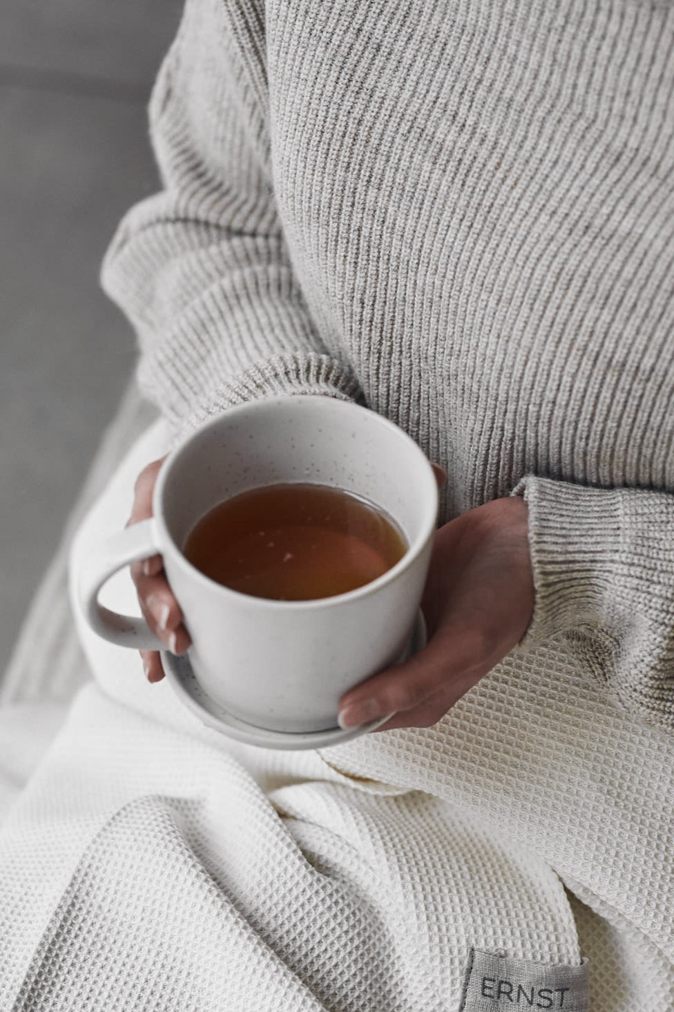 Someone enjoying a cup of tea for a white Ernst cup and saucer during a Swedish fika.