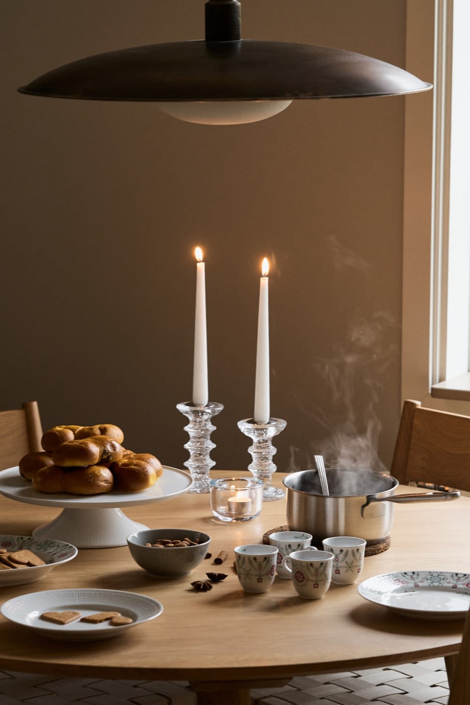 A cosy Christmas table set with saffron buns, mulled wine and Christmas tableware. 