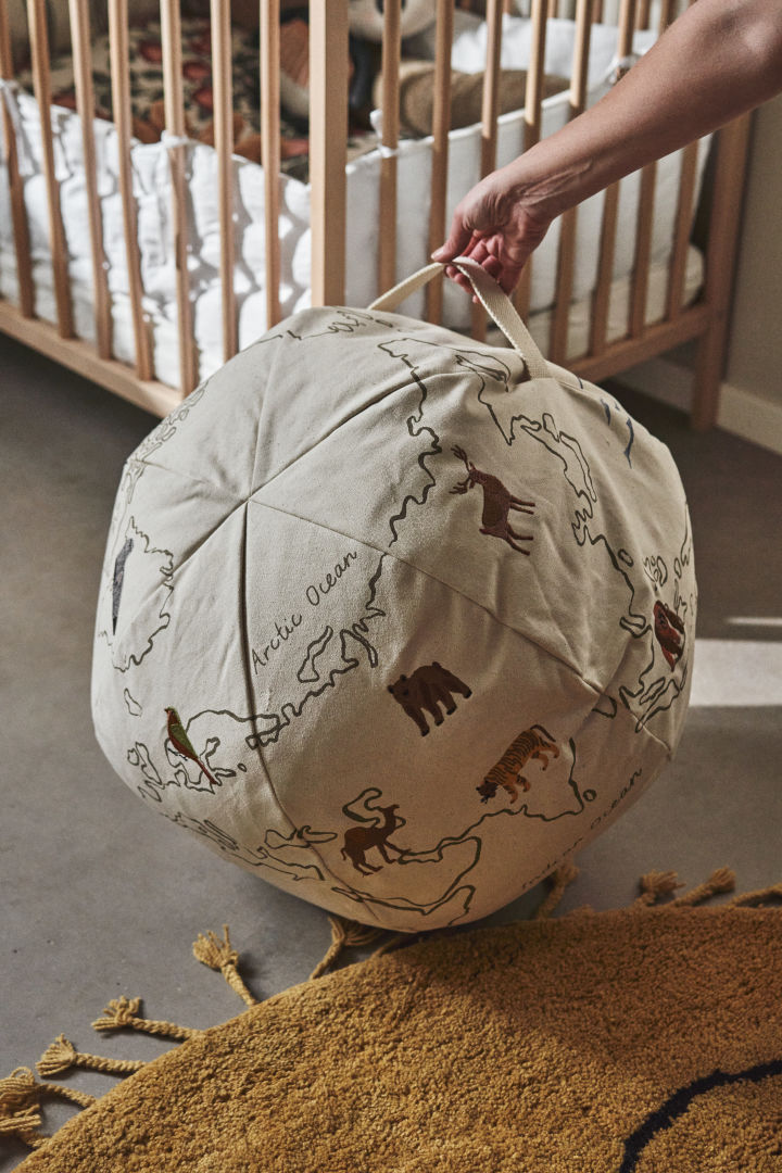 A world map and bean bag in one, here you see a hand holding the World pouf from Ferm Living, a great idea for a children's room. 