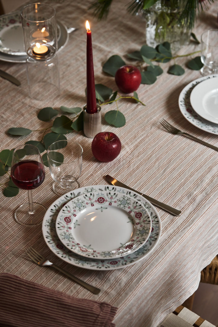 A simple Christmas table setting idea with Swedish Grace Winter, red candles and greenery. 