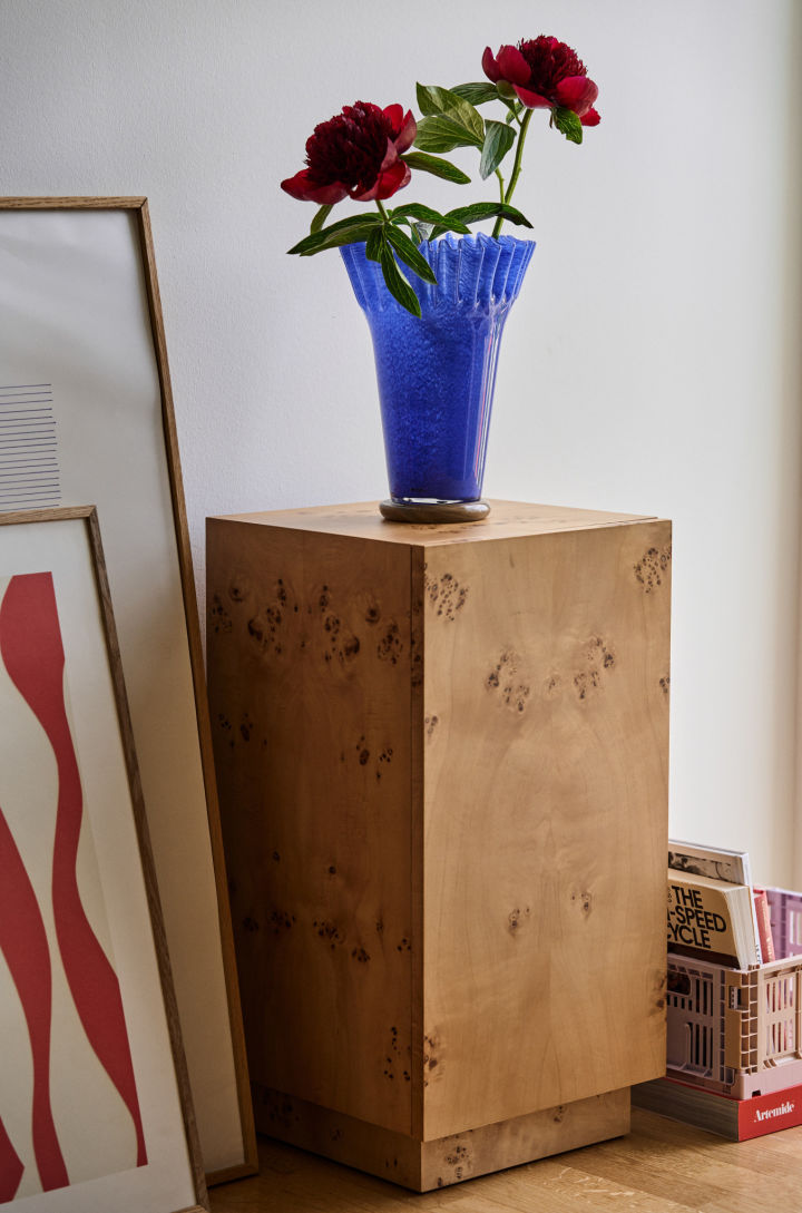 The interior design trends for autumn 2024 are a mix of playfulness and retro. Here you see the blue Lori vase from Byon with deep red peonies and the burl side table from Ferm Living. 