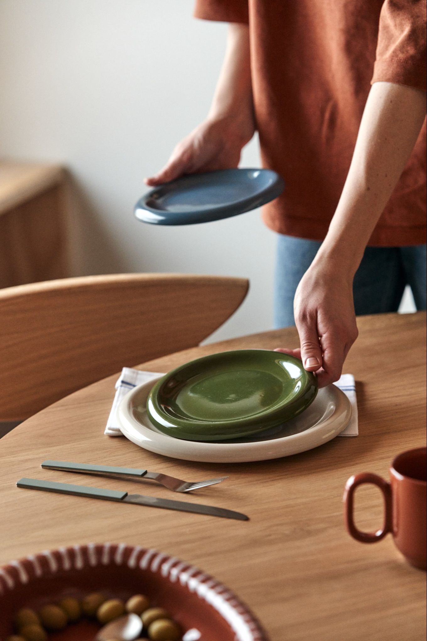 The chunky design trend is here to stay for autumn 2024, here you see someone setting the table with the chunky porcelain set Barro from HAY in the autumns trendiest colours. 