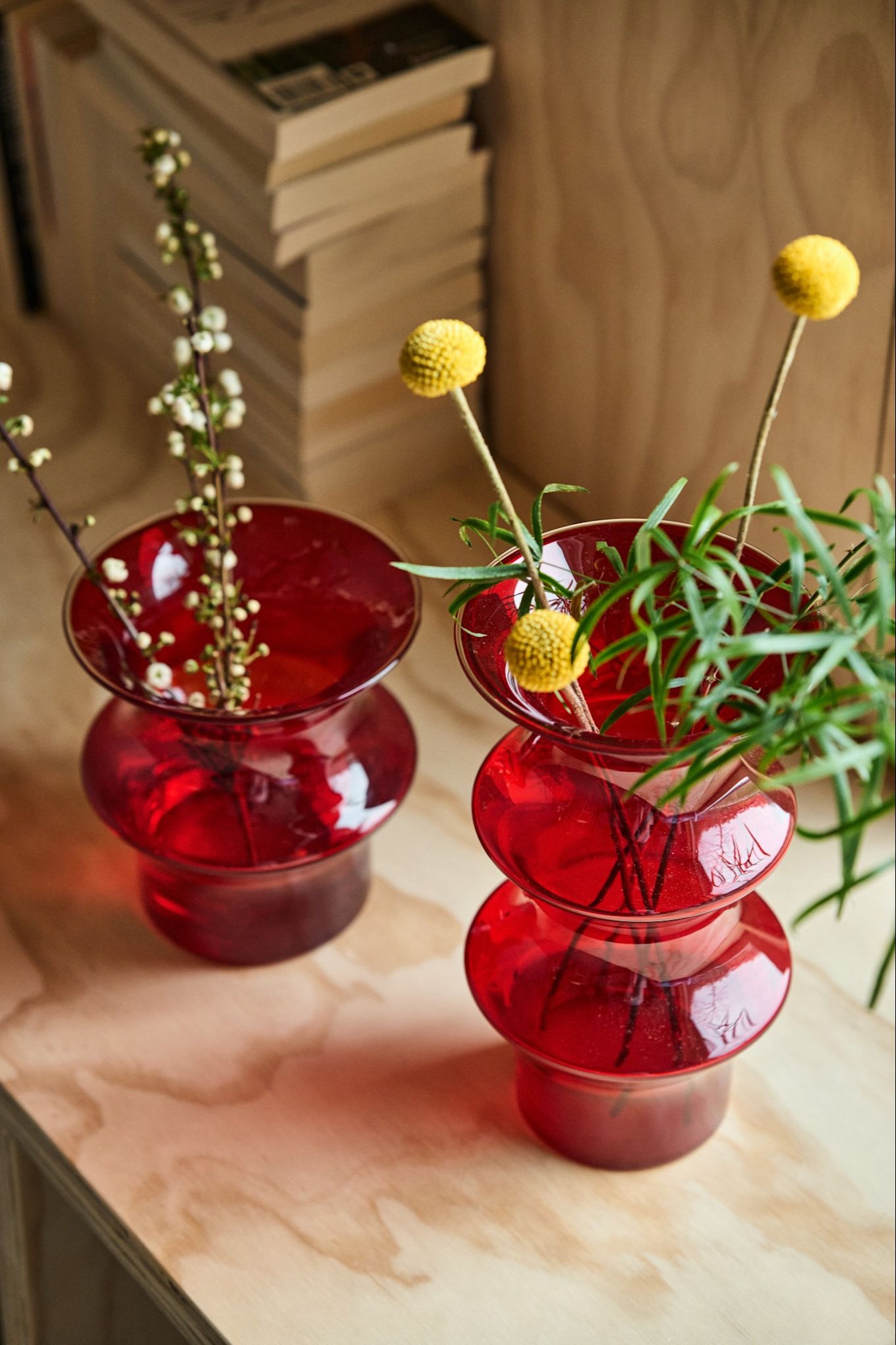 Two red Pagod vases stand next to each other on a plywood bench.