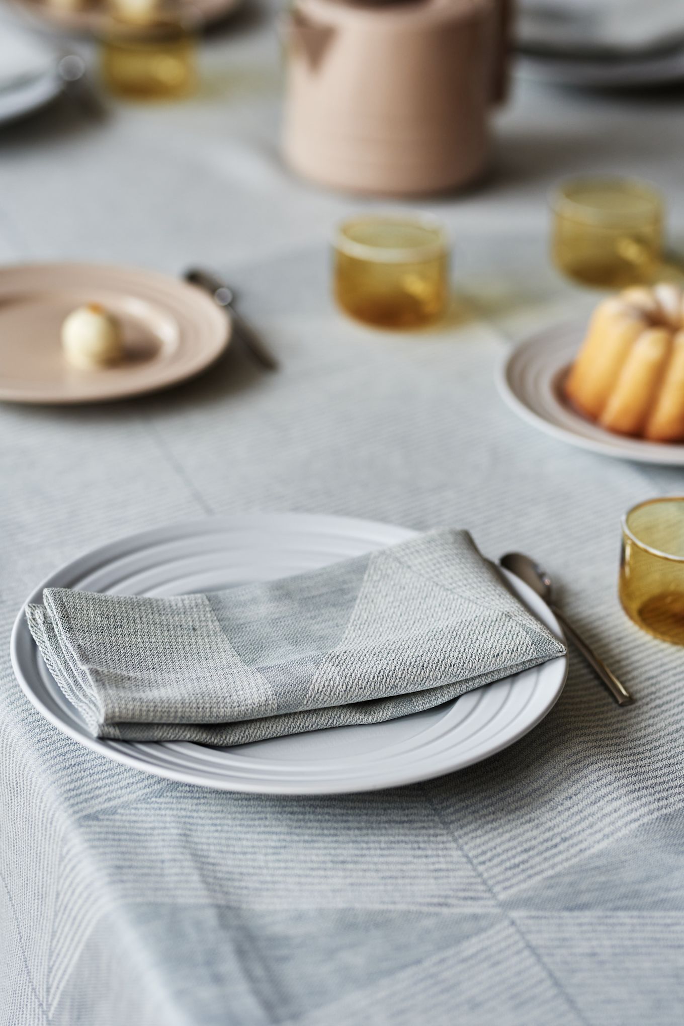 An elegant table setting idea in soft pastels with a sky blue tablecloth from NJRD and delicate beige and yellow elements. 