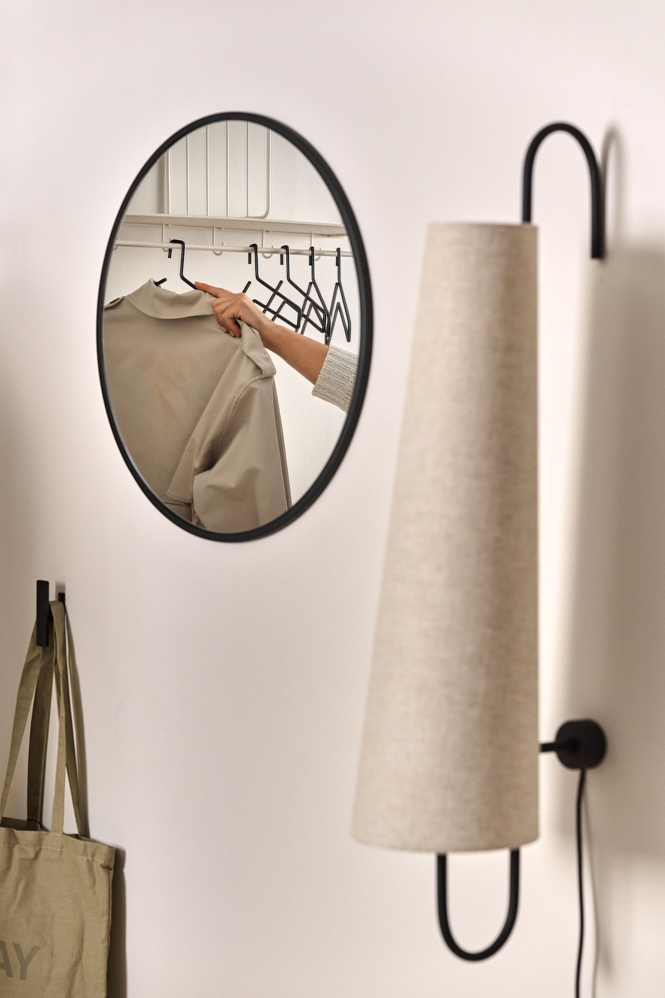 A mirror can make a small hallway look bigger. Here you can see the black Sphere mirror from Scandi Living, in which a hat shelf with coat hooks is reflected.