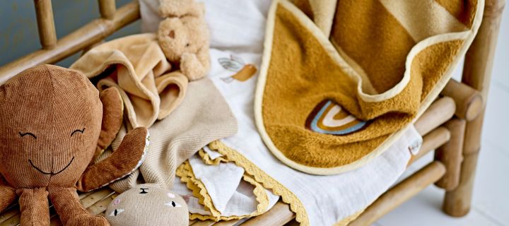 A hooded towel lays over the arm of a bench with a toy octopus and a comforter - ideal baby shower gift ideas. 