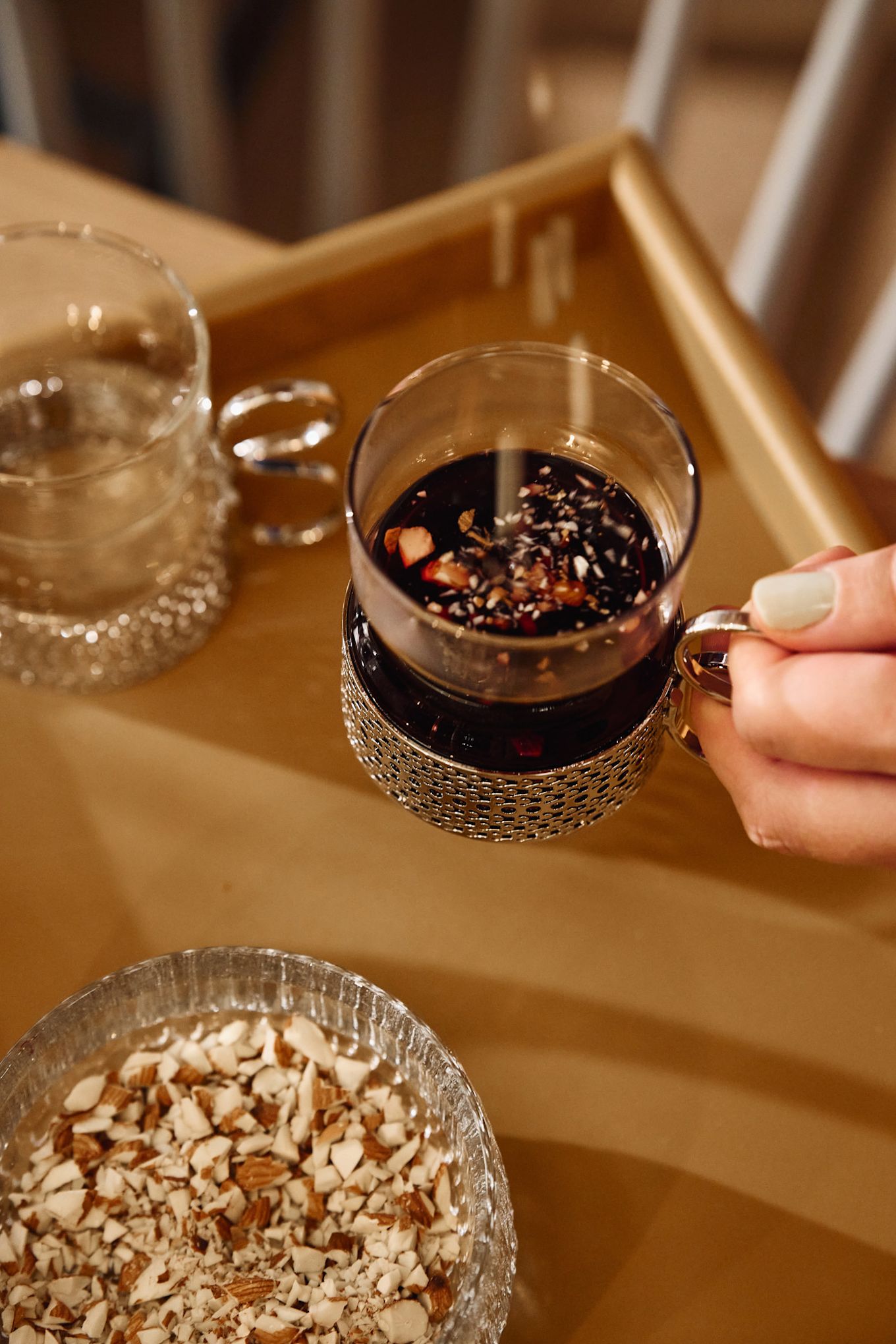 Someone sprinkles almonds into a glass filled with Swedish glögg or mulled wine. 