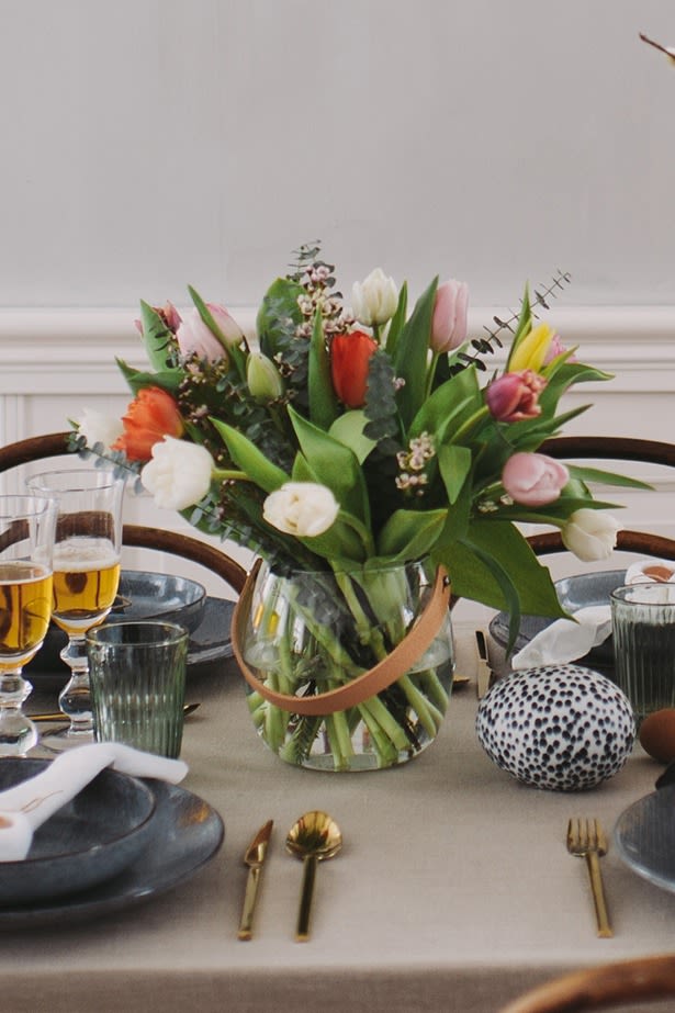 A colourful bouquet of tulips stands on the table as a beautiful and natural decoration on a rustic Easter table setting.