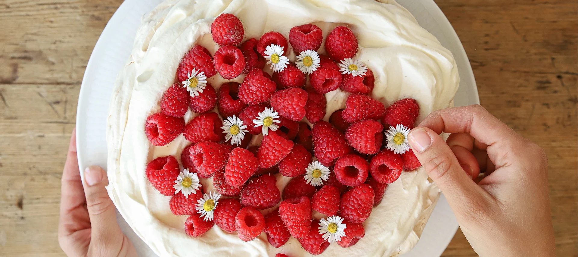 A delicious meringue cake is one of Baka med Frida's simple cake recipes. Decorate the white meringue and cream cake with fresh red raspberries and pretty daisies.