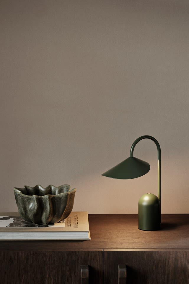 Moss green is one of the autumn interior design trends in autumn 2024, here you see the portable Arum table lamp in moss green from ferm LIVING. 