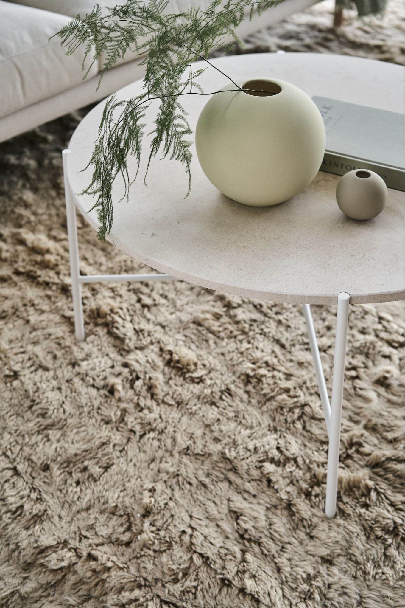 The iconic Ball vase in shell and sand from Cooee Design on a coffee table in a Scandinavian style living room. 