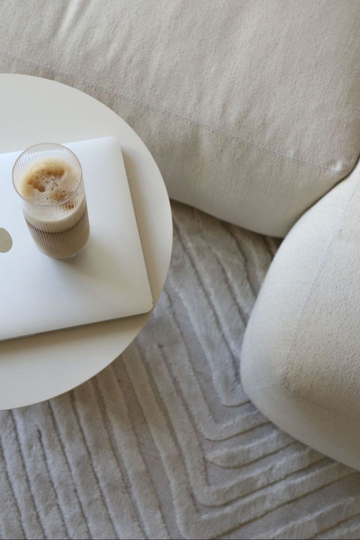 Here you can see a perfectly prepared latte macchiato in a long drink glass from the Ripple collection by Ferm Living, which stands on a coffee table next to a beige-coloured couch in @ellesklingen's home.